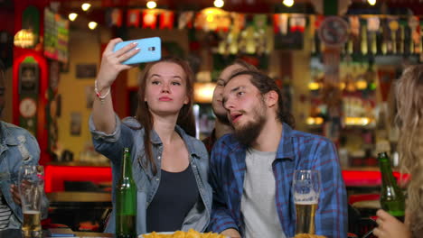 Friends-take-pictures-on-the-phone-at-the-bar-make-a-shared-photo-on-the-phone.-Party-with-friends-at-the-bar-with-beer.